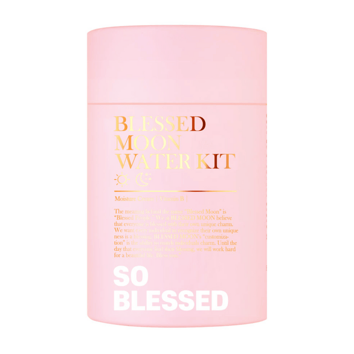 Bilden visar en rosa cylinderformad förpackning med texten "Blessed Moon Water Kit". Texten är i guld och vitt, och produkten verkar innehålla fuktgivande krämer berikade med vitamin B. På förpackningen står det även en beskrivning om varumärket Blessed Moon och deras filosofi om att varje individ har sin unika charm.