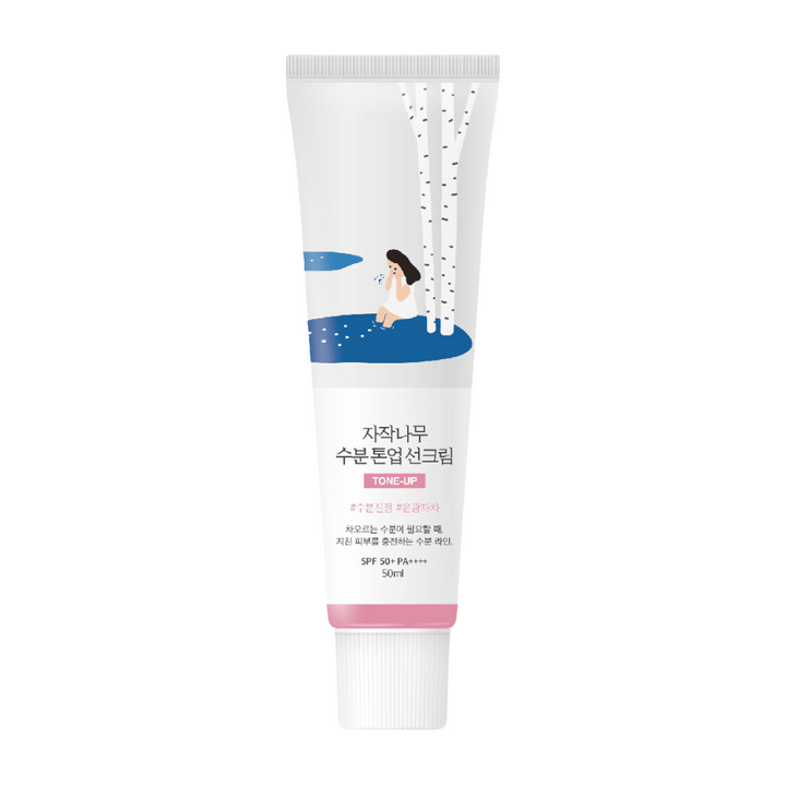 En vit tub med Birch Juice Moisturizing Tone Up Sunscreen. Tuben har en illustration av en kvinna som sitter vid en björk bredvid en vattenpöl. Texten på tuben är på koreanska och anger att produkten har SPF 50+ PA++++ och innehåller 50 ml.