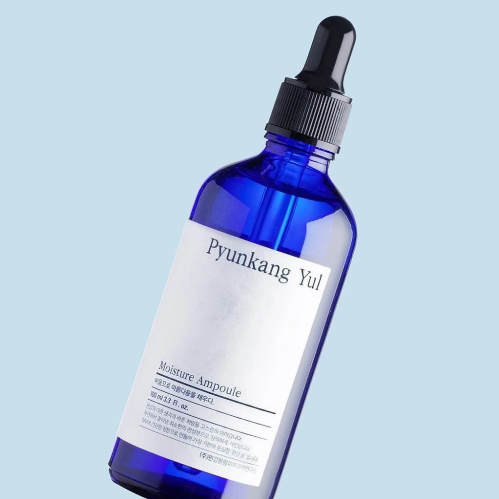 En blå flaska på blå bakgrund med Pyunkang Yul's Moisture Ampoule 100ml serum.